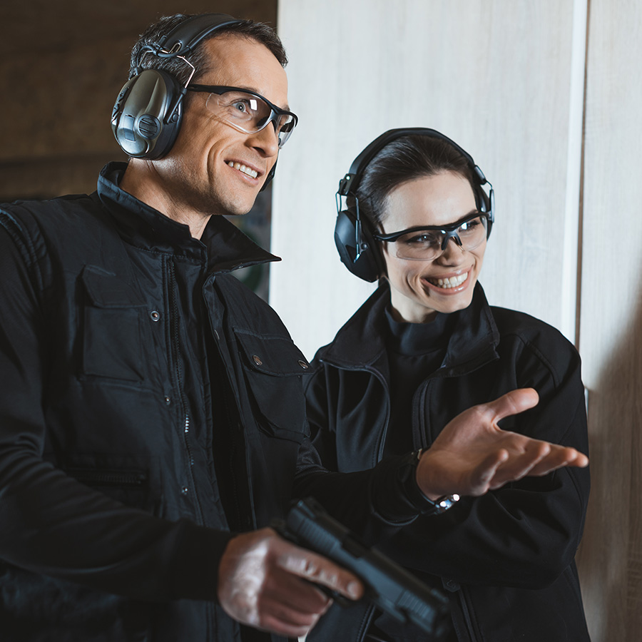smiling shooting instructor and customer in shooti DQQ2E9E