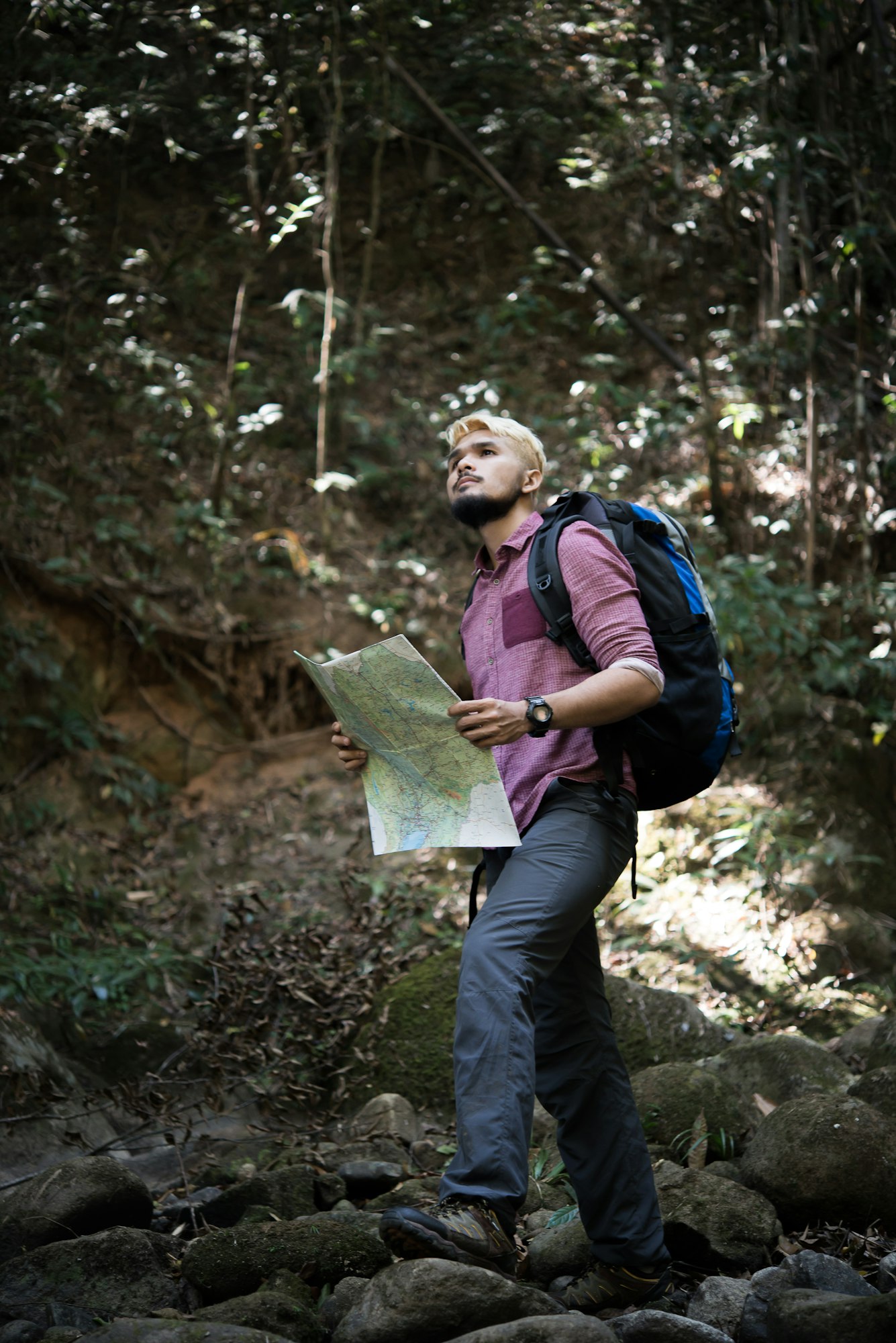 adventure man observing map on a mountain path to find the the right way