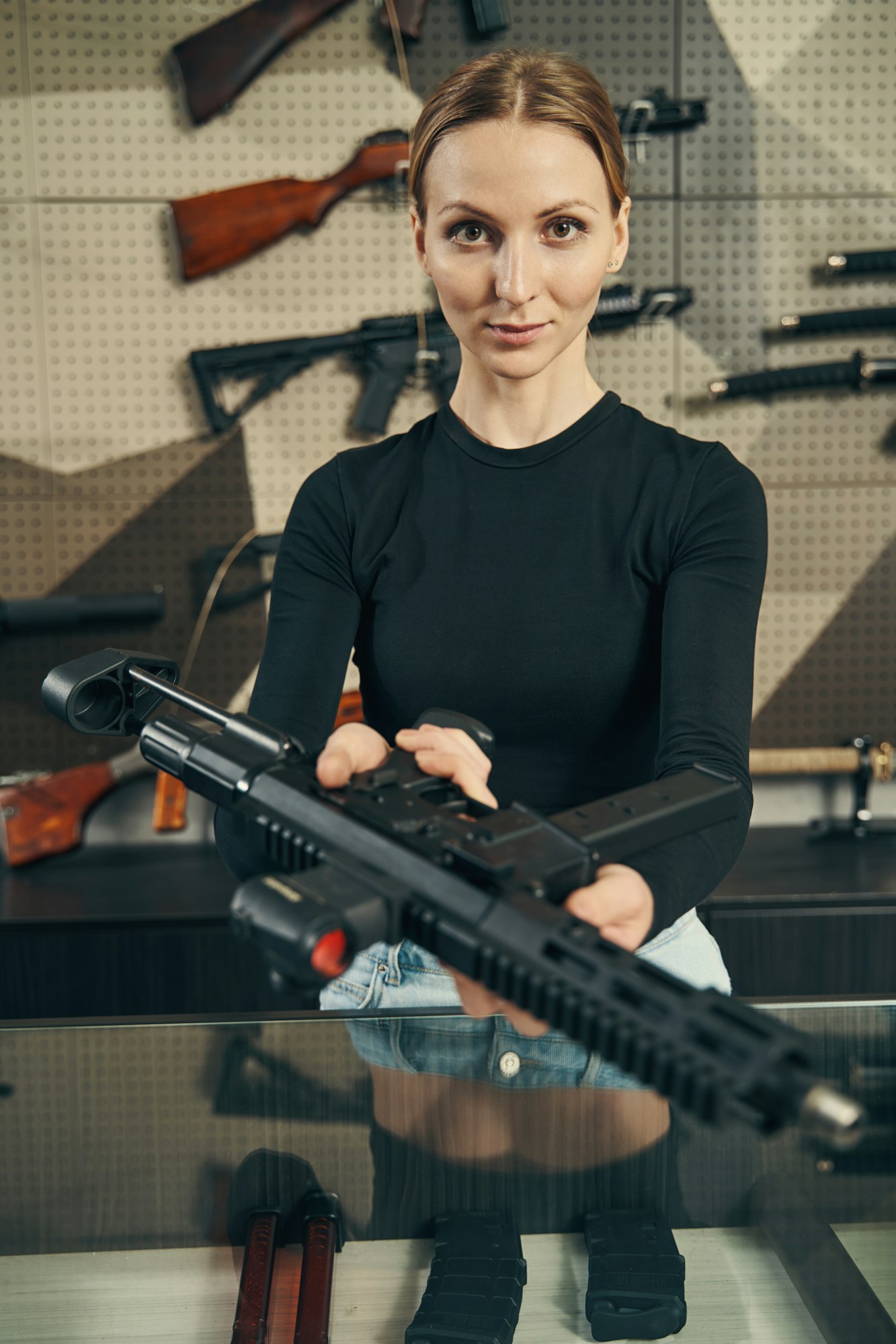 experienced caucasian saleswoman demonstrating an unloaded firearm